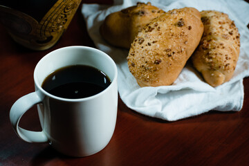 coffee falling into a white porcelain cup with bread next to it on a white handkerchief