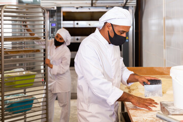 Professional baker dividing raw dough into equal parts and weighing them. Bread making process in bakery