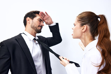 Man and woman pulling on tie anger business looking at each other screaming with hands up in white isolated background. The concept of business in a couple harassment startup copy space