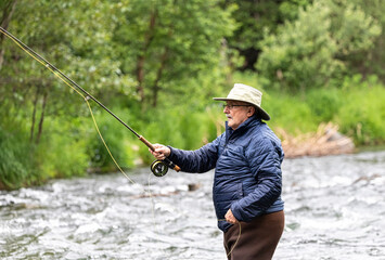 An older man tries his luck at fly fishing for salmon.  Russian River.  Cooper Landing, Alaska.