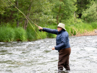 An older gentleman tries his luck at fly fishing for salmon.  Russian River.  Cooper Landing, Alaska.
