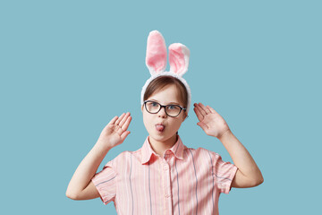 Portrait of teen girl with Down syndrome wearing Easter bunny ears against blue background and...