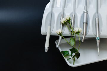Close-up of dental chair tools and white rose on left in background.