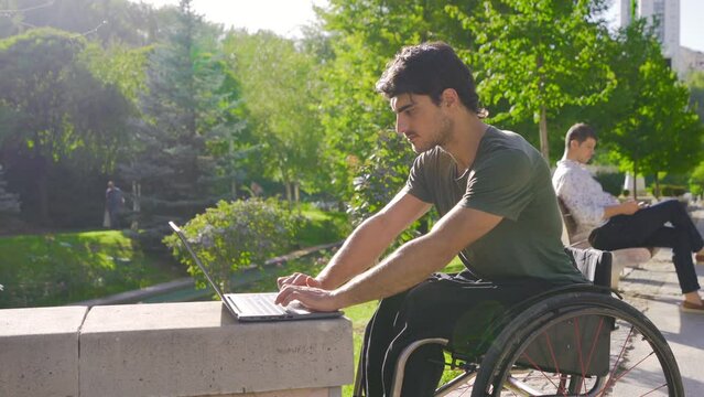 Disabled young man working with laptop.
Freelancer, young disabled man working outside with laptop.
