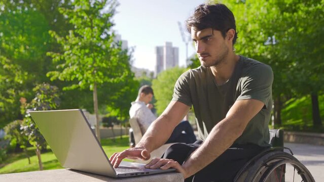 Disabled young man working with laptop and earning, rejoicing.
Freelancer, young disabled man working outside with laptop.

