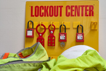 lockout/tagout station with tagout and locks attached surrounded by safety vest and white hard hat