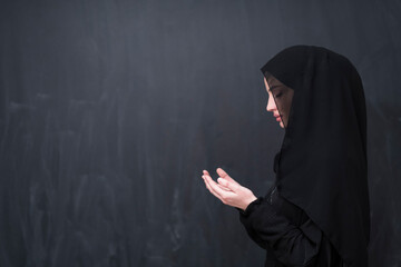 Portrait of beautiful muslim woman in fashionable dress with hijab making traditional prayer to God...