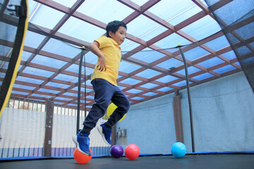 Hispanic 6-year-old boy jumping on a brincolin as a physical activity for a healthy life he exercises and has fun alone at home
