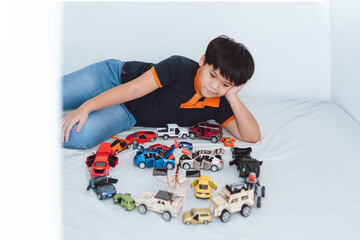 Little boy is playing with colored toy cars at home. 