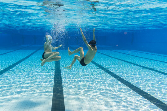 Two Kids Playing Underwater At Summer Day