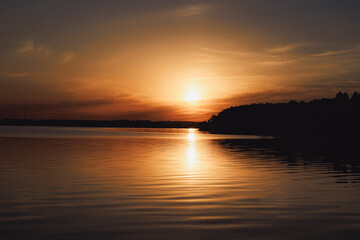 Beautiful sunset of a warm summer evening on the shore of a quiet lake