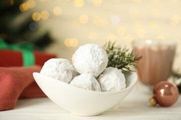 Ceramic bowl with tasty Christmas snowball cookies on white table, closeup