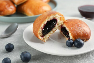 Delicious baked patties with jam and blueberries on light grey table, closeup