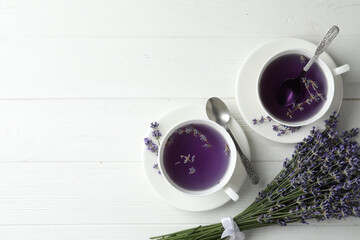 Fototapeta Fresh delicious tea with lavender and beautiful flowers on white wooden table, flat lay. Space for text obraz