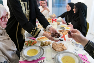 modern multiethnic muslim family sharing a bowl of dates while enjoying iftar dinner together during a ramadan feast at home