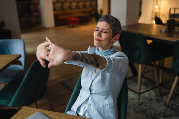 one woman stretch back and arms at cafe taking a brake from work