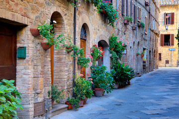 Fototapeta na wymiar Italy, Tuscany, Pienza. Flower pots and potted plants decorate a narrow street in a Tuscany village.
