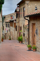 Fototapeta na wymiar Italy, Tuscany, San Gimignano. Homes decorated with flower pots along the streets of San Gimignano.
