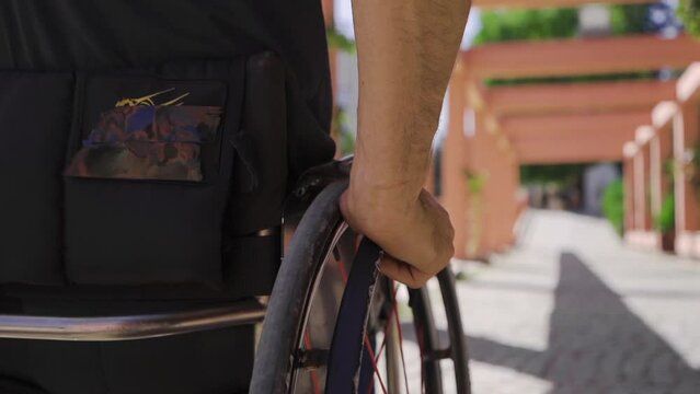 Close-up of disabled young man using wheelchair in slow motion.
Man sitting in a wheelchair in slow motion drives the chair.
