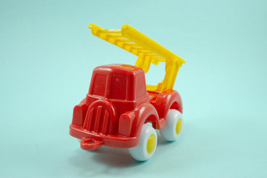 Red paint plastic toy fire truck with yellow ladder isolated on turquoise