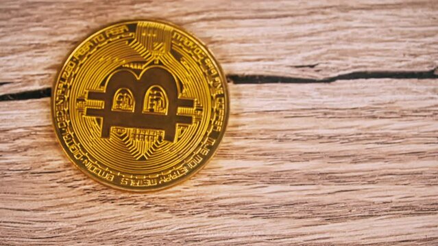 Gold bitcoin coin rotates in slow mo on the table close-up. Cyberspace of digital coins and cryptocurrencies. Crypto exchange and digital coins.