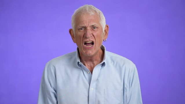 Displeased irritated sad angry elderly gray-haired man 70s wears blue shirt yell scream isolated on plain light purple background studio portrait