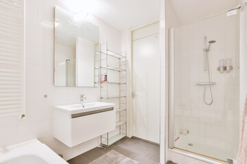 Fototapeta na wymiar Sinks with mirrors and clean bathtub located near shower box with glass door in modern bathroom with white tiled walls