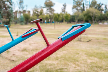 High quality photography. Blue and red swings in the empty park full of grass and nature. Park for children to play.