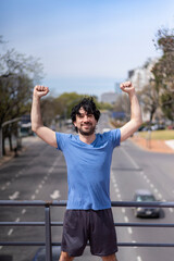 Successful man raising arms after running. Fitness male athlete with arms up celebrating success and goals after sport exercising .