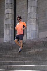 Fototapeta na wymiar Portrait of handsome attractive mature bearded athletic latin man guy 40s in orange t-shirt running on some stairs