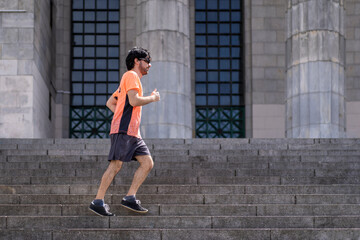 Portrait of handsome attractive mature bearded athletic latin man guy 40s in orange t-shirt running on some stairs