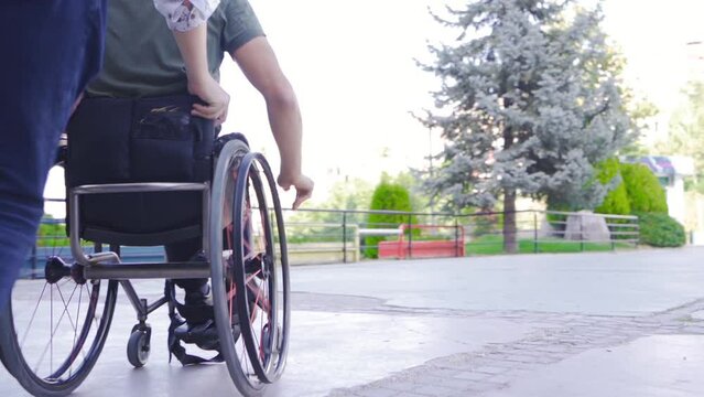 Disabled young man having fun in wheelchair in slow motion.
Two friends happily having fun and helping her disabled friend use his wheelchair.
