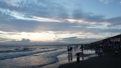 FUJISAWA, KANAGAWA, JAPAN - AUGUST 2022 : View of Enoshima beach (sea) at Shonan area in sunset. Romantic, moody sky in dusk. Japanese hot summer holiday (vacation) season concept video.