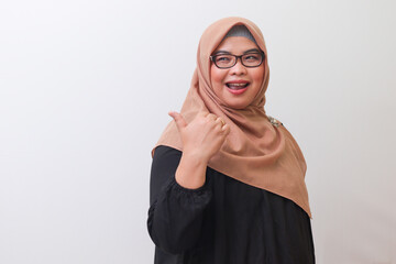 Portrait of cheerful Asian woman with hijab, making thumbs up hand gesture. Isolated image on white background