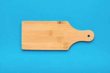 Classic wooden cutting board on a light blue background. Flat lay.