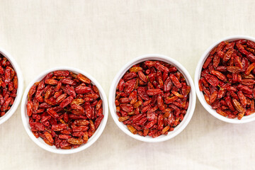 Dried Barberry berries in round ceramic white plates, top view on table. Ripe dry sour-tasting berries, healthy seasoning for food. Red Barberry natural food. Healthy and tasty spice
