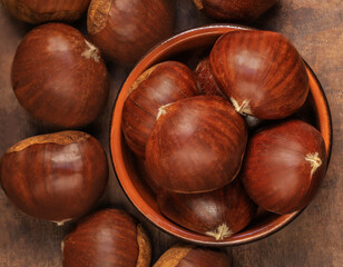 Chestnuts in a bowl  on a wooden background. Autumn fall seasonal composition with horse chestnuts .