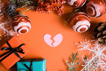 割れたハートとクリスマスの装飾品と赤背景の写真