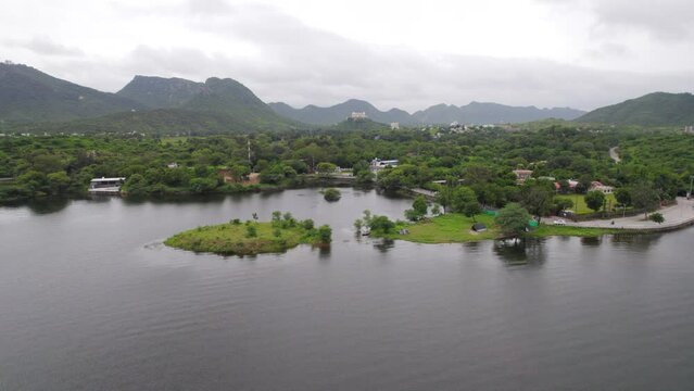 Drone flying over Fateh Sagar lake and Sajjangarh Monsoon palace in background. Tropical landscape in India. 4K
