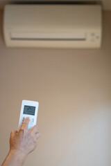 Close-up of old Woman hand operating Air Conditioner With Remote Control. copy space