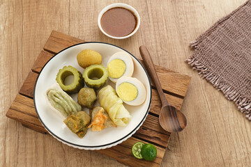 Siomay Bandung (Shumay) or steamed dumplings with boiled egg, tofu, potatoes and cabbage roll. Indonesian traditional street food with peanut sauce and soy sauce, and green lime.
