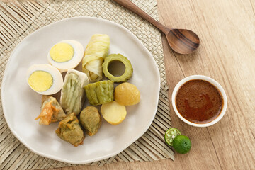 Siomay Bandung (Shumay) or steamed dumplings with boiled egg, tofu, potatoes and cabbage roll. Indonesian traditional street food with peanut sauce and soy sauce, and green lime.
