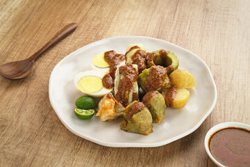 Siomay Bandung (Shumay) or steamed dumplings with boiled egg, tofu, potatoes and cabbage roll. Indonesian traditional street food with peanut sauce and soy sauce, and green lime.
