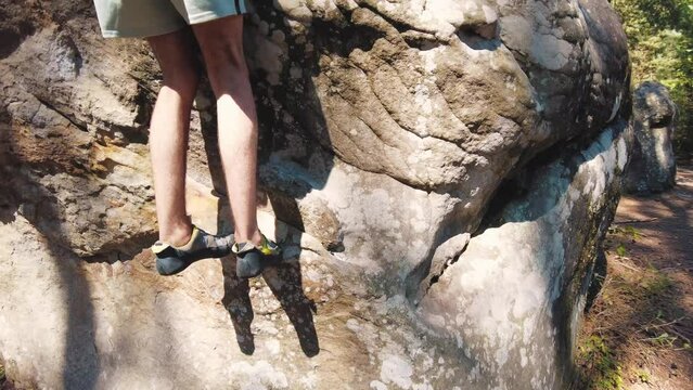 young man's lower half in climbing shoes tiptoeing climb over small edge boulder