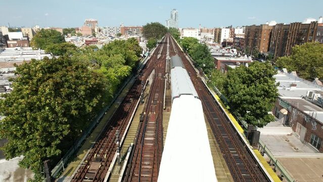 An aerial view of train tracks with three vintage train cars travelling away from the camera on a sunny day. The R10, R7a and a R16 are historic. The camera is stationary over the the elevated tracks.