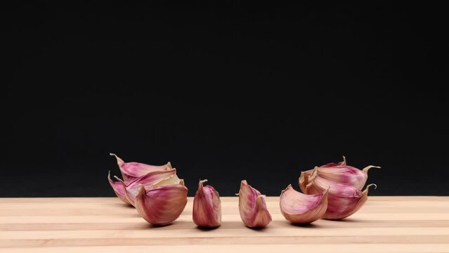 Head of garlic jumps, impacts and tears apart into garlic cloves. Stop motion animation.