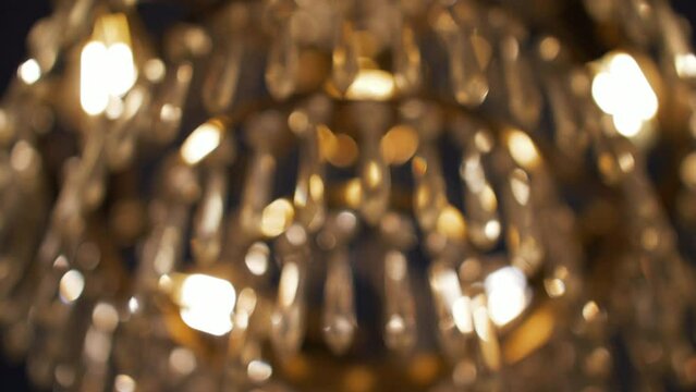 Low angle closeup of crystal candelabrum ceiling, warm temperature light