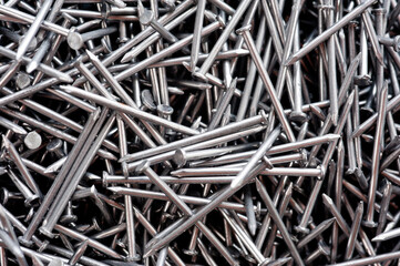 Small thin metal nails, hardware, lying in a round container.