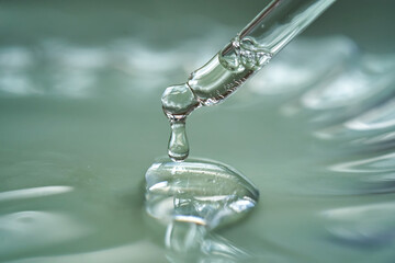 Dropper with serum or cosmetic oil on a green background.