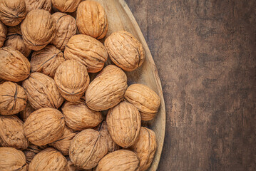 Walnuts on dark vintage table top view. Fresh Walnuts kernels in wooden plate. Copyspace